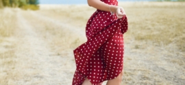 femme en robe à pois rouges debout au milieu d'un champ d'herbe pendant la journée, féminisation