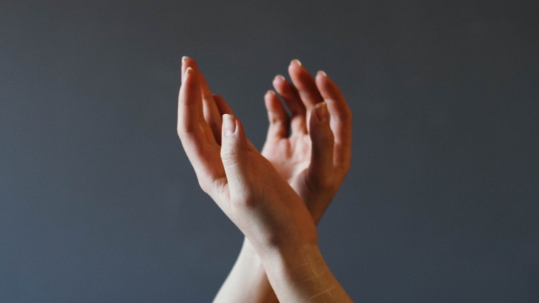 Was ist weibliche Energie? 1 linke Hand über rechter Hand mit grauem Hintergrund