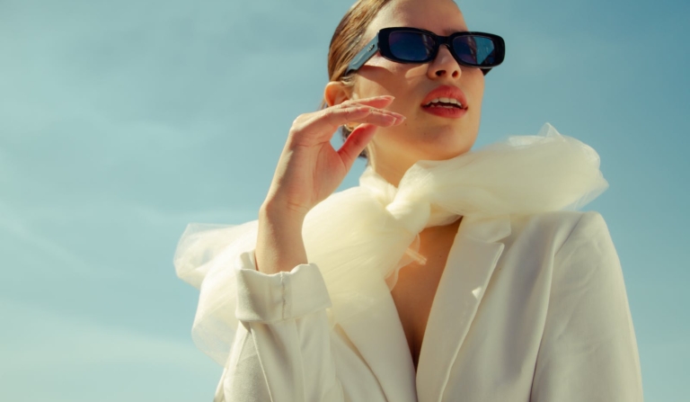 Low angle of stylish female model in sunglasses standing with opened mouth and looking away