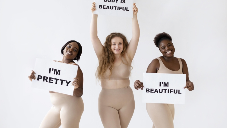 Reclaiming Body Positivity and Embracing Diverse Body Shapes 1 three women holding placards with body positivity statements