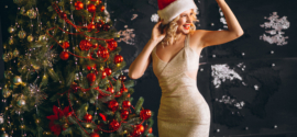 young woman dress with christmas presents by christmas tree
