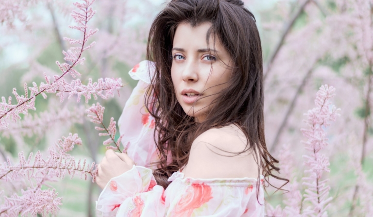 Frau steht neben einer Pflanze mit rosa Blättern